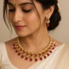 Close up of kundan necklace set with red beads and pearls worn by woman traditional jewellery design